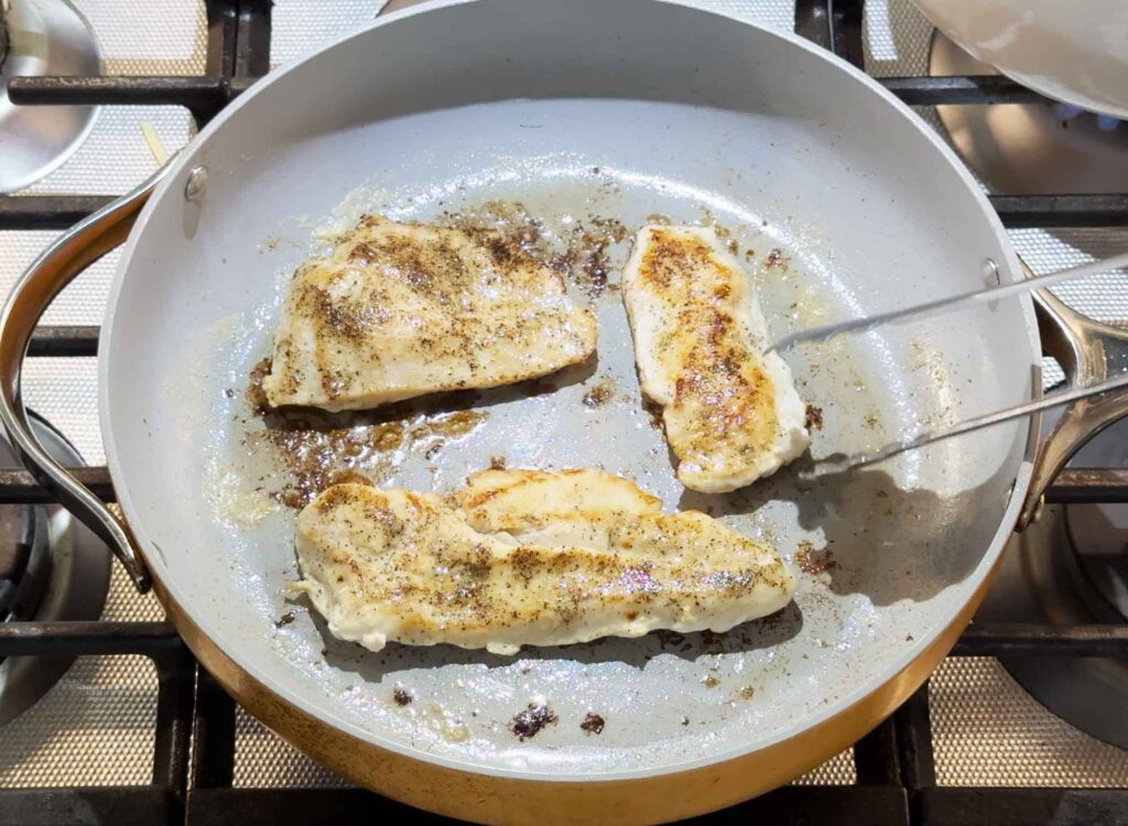 Searing the seasoned chicken breasts