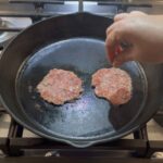 Seasoning the smash burgers.