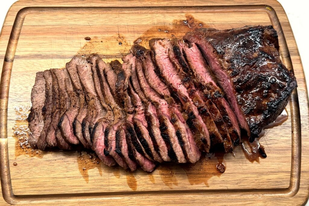Slicing the marinated steak across the grain on a cutting board