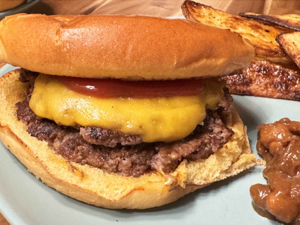 Smash burger with cheese and ketchup on a dinner plate