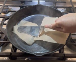 Pressing on the burgers with a piece of parchment paper covering them.