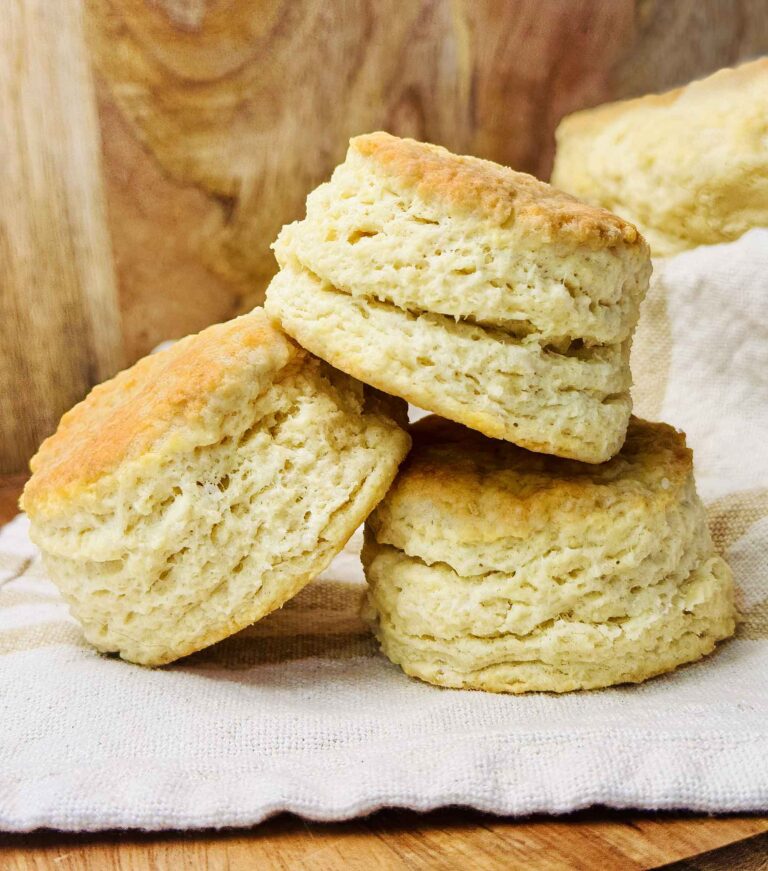 A stack of soft sourdough discard biscuits served on a wood board with a napkin