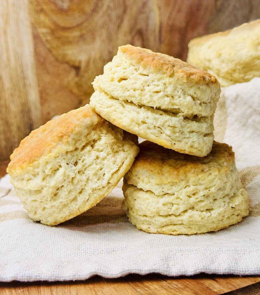A stack of soft sourdough discard biscuits served on a wood board with a napkin