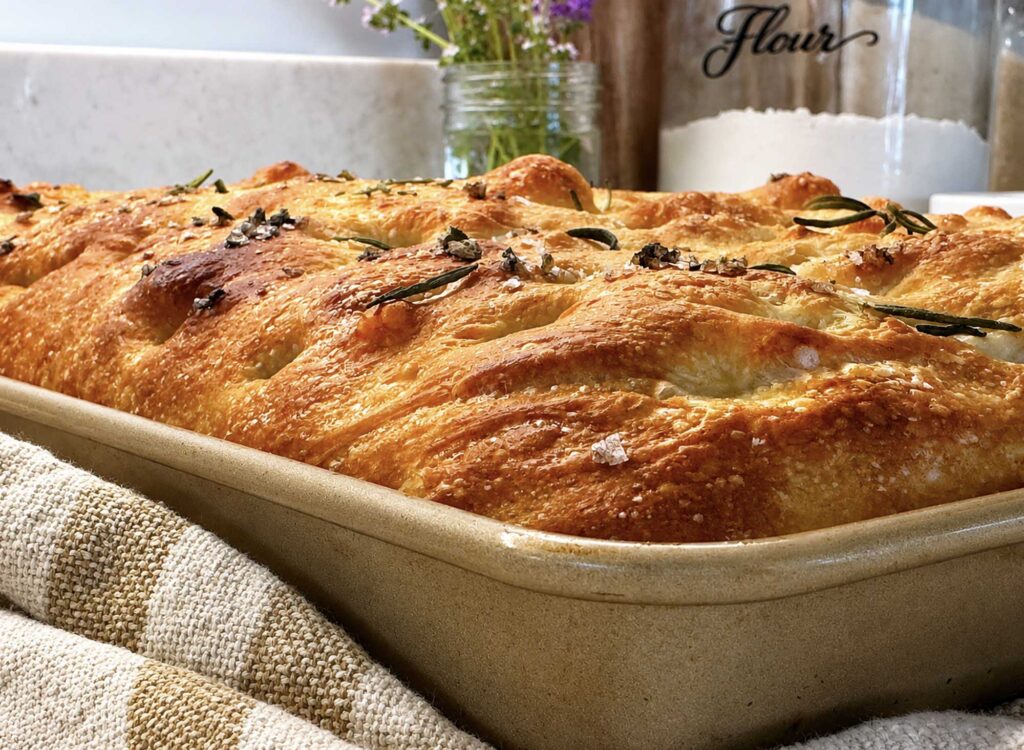 A loaf of sourdough focaccia in a metal baking pan