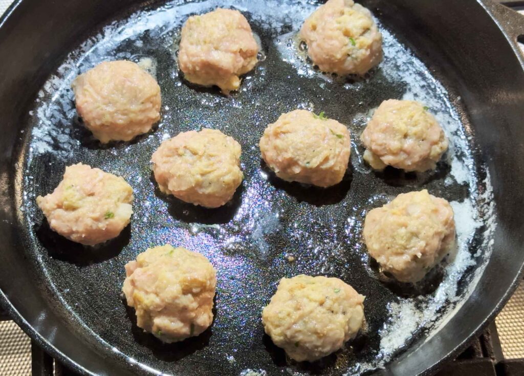 Raw turkey meatballs in a cast iron skillet