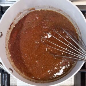 mixing sauce ingredients in the sauce pan with a whisk