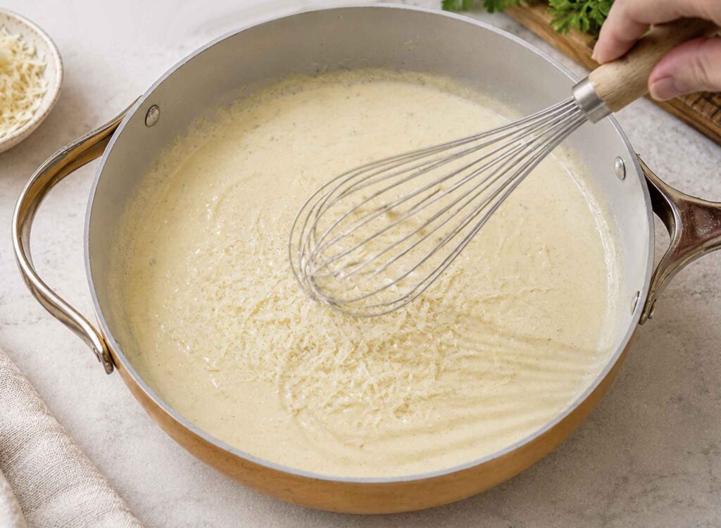 Whisking in Parmesan cheese to alfredo sauce