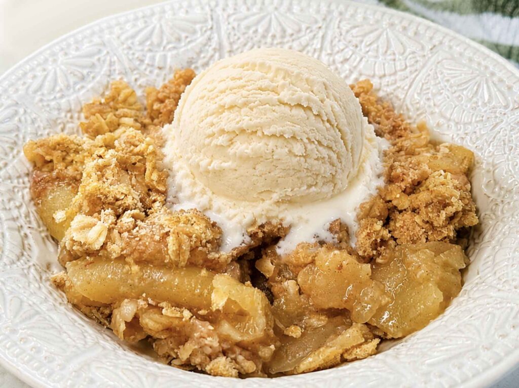 Warm apple crisp with a scoop of vanilla ice cream melting into it