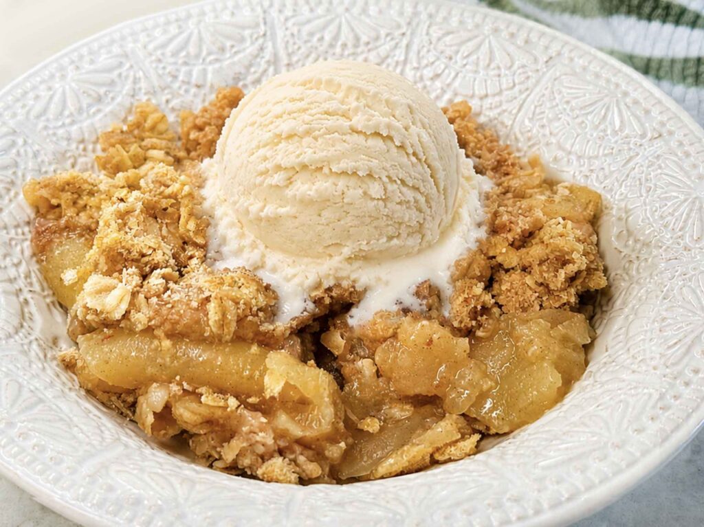 Warm apple crisp with a scoop of vanilla ice cream melting into it