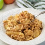 A bowl of baked apple crisp with a buttery oat topping and juicy apples