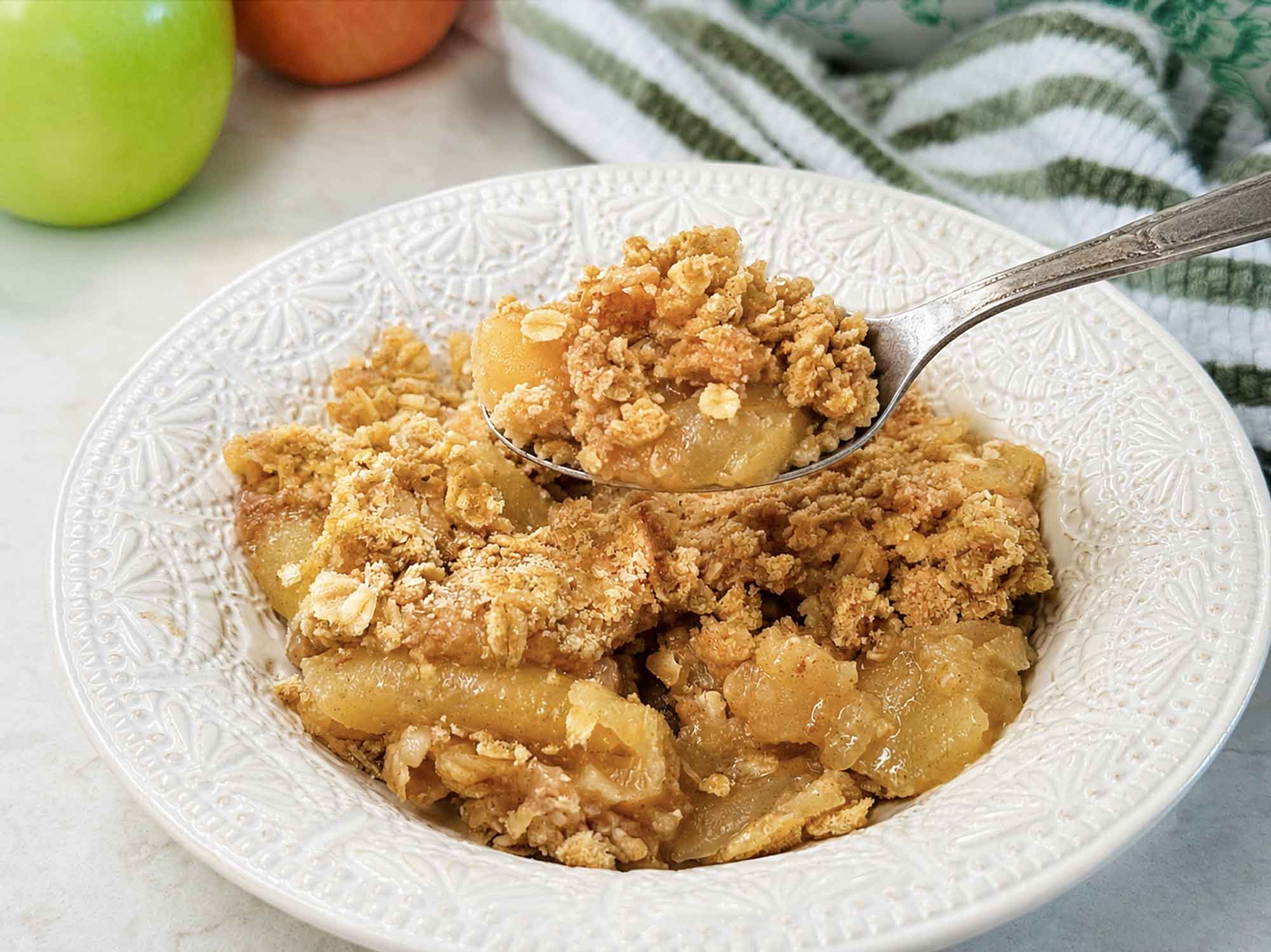 A bowl of baked apple crisp with a buttery oat topping and juicy apples