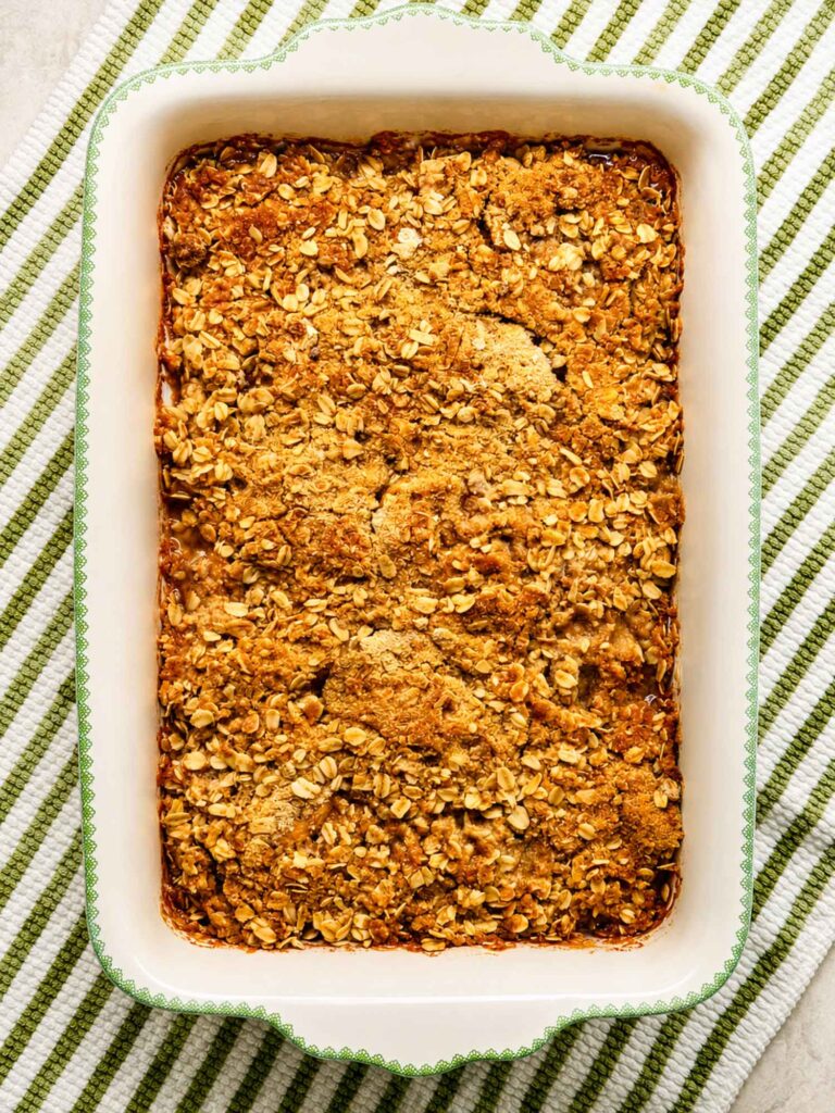 Freshly baked apple crisp with an oatmeal topping in a ceramic baking dish
