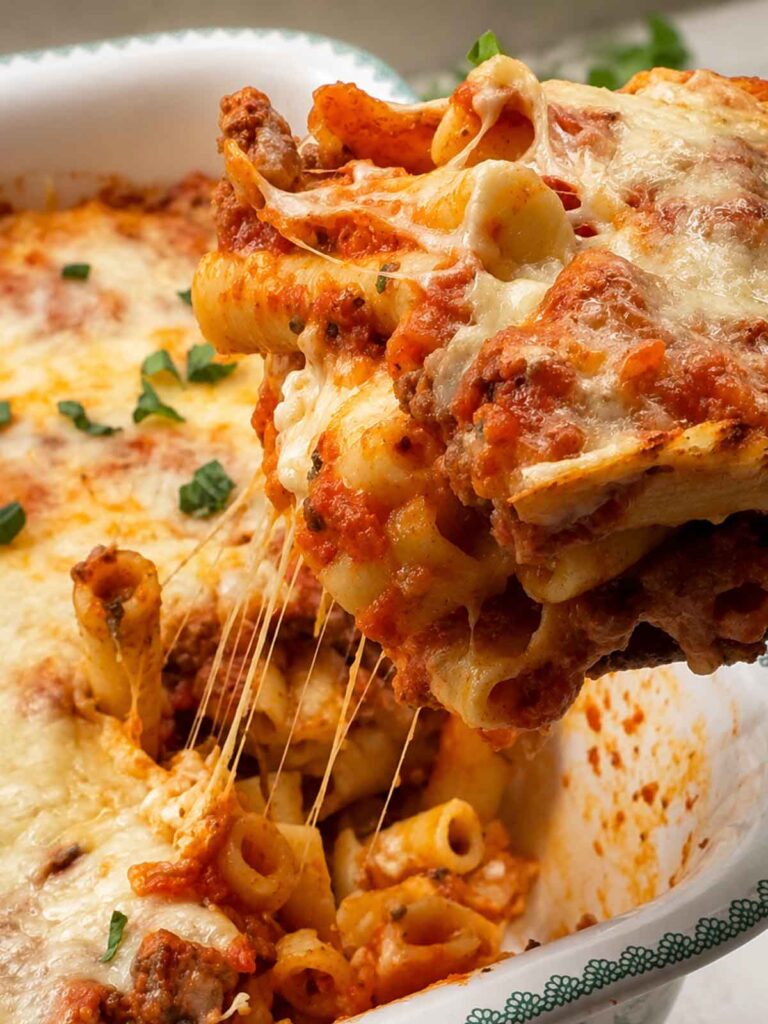 A cheesy scoop of baked ziti lifted from the dish with long strands of melted mozzarella