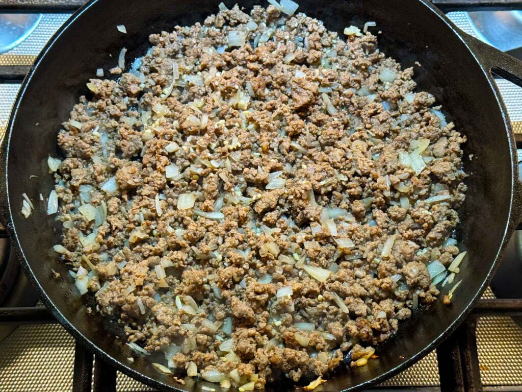 Browning the ground beef and onions in a cast iron skillet