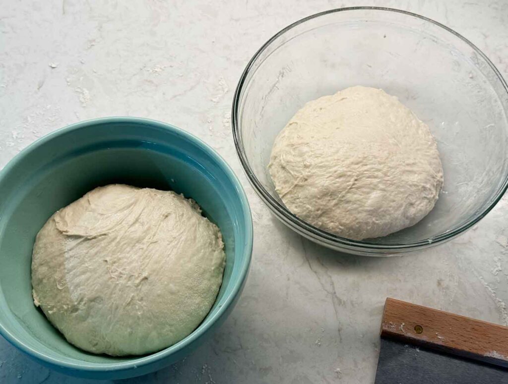 Two bowls of divided sourdough pizza crust dough resting