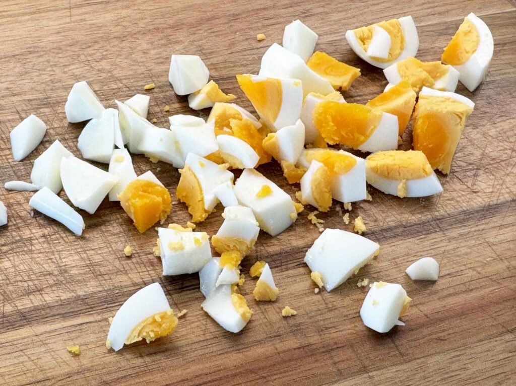 Hard-boiled eggs chopped into a rough dice on a wooden cutting board