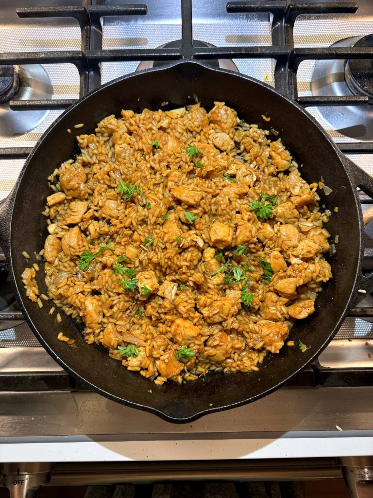 The finished one-pot honey BBQ chicken and rice in the skillet, garnished with parsley.
