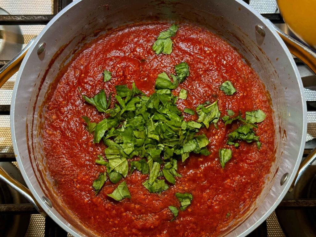 fresh basil in a big pot of spaghetti sauce