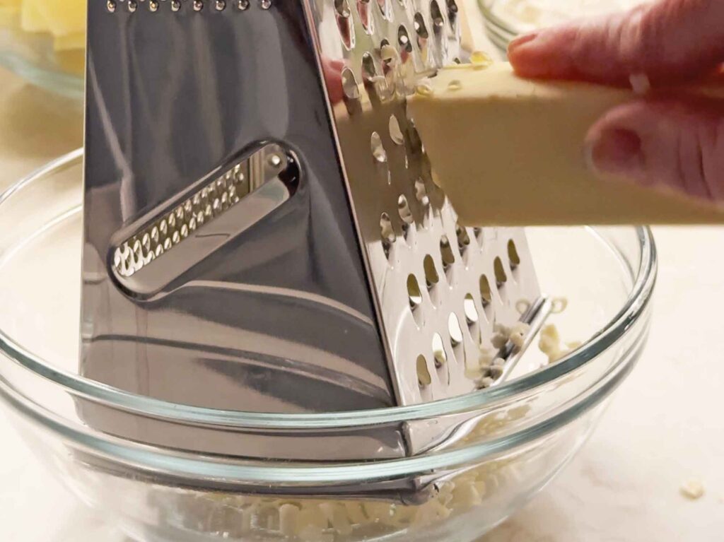 grating frozen butter on a box grater for apple crisp topping