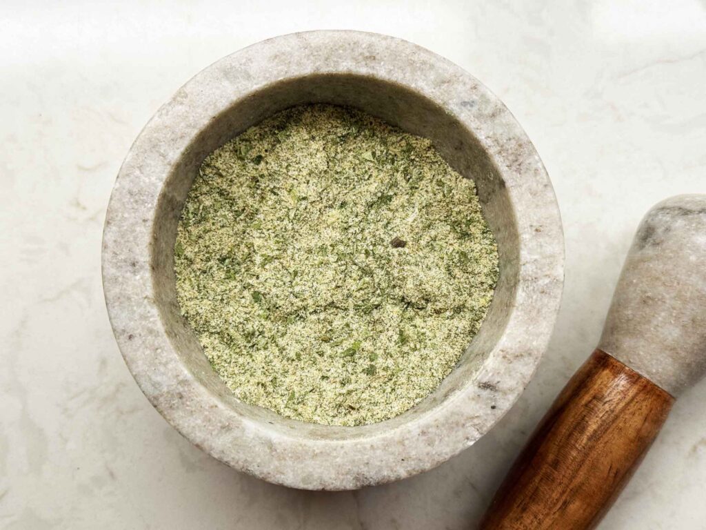 Grinding ranch seasoning mixture to a fine powder with a mortar and pestle
