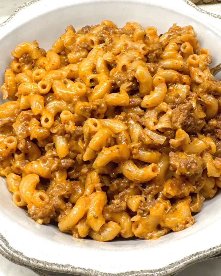 Homemade Hamburger Helper with ground beef and elbow macaroni in a creamy cheddar sauce, served in a white bowl.