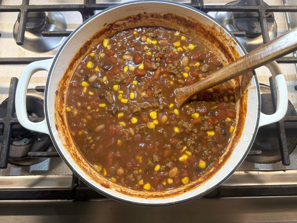 Taco soup simmering in a pot on the stovetop with a wooden spoon