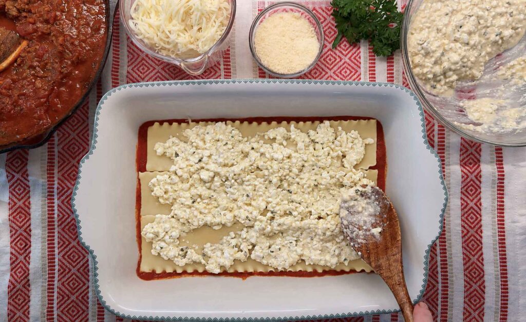 Layering a lasagna with pasta sauce, noodles, and cheese mixture