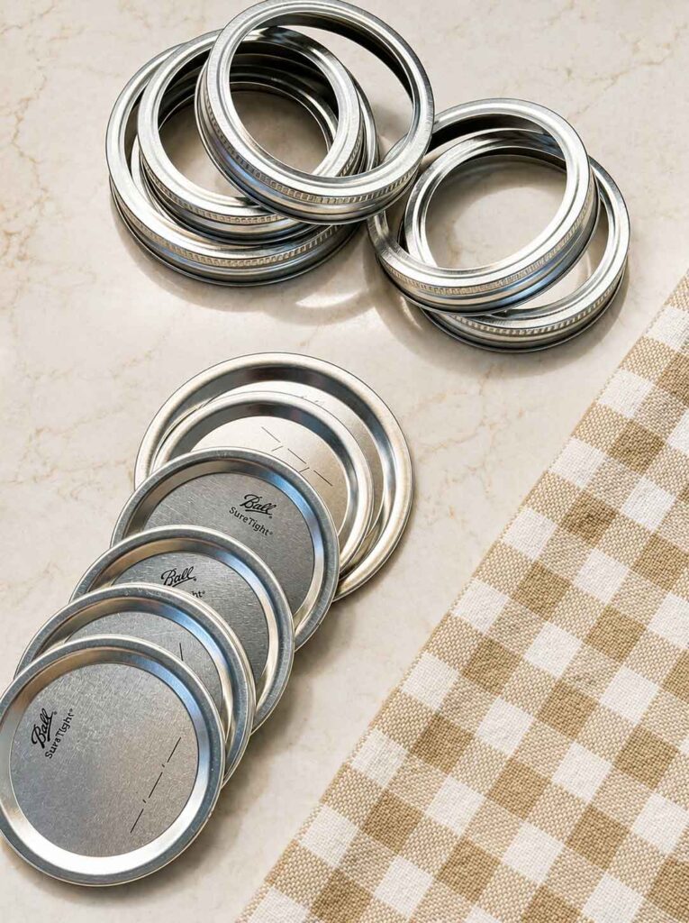 New flat canning lids and screw bands stacked on the counter