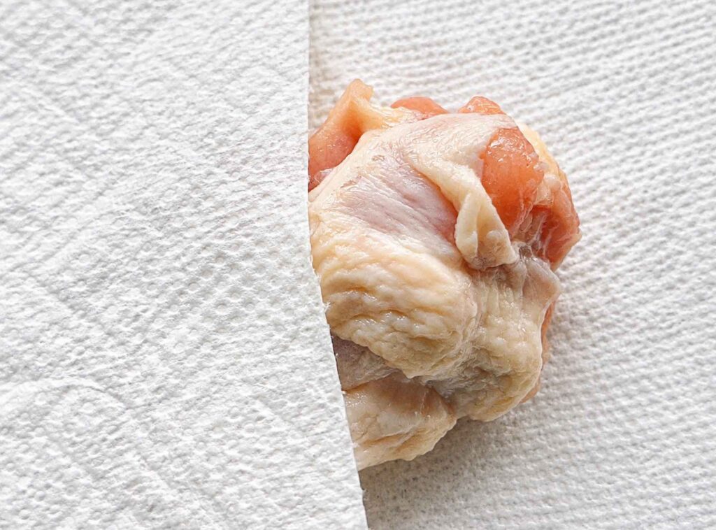 Patting a raw chicken wing dry with a paper towel
