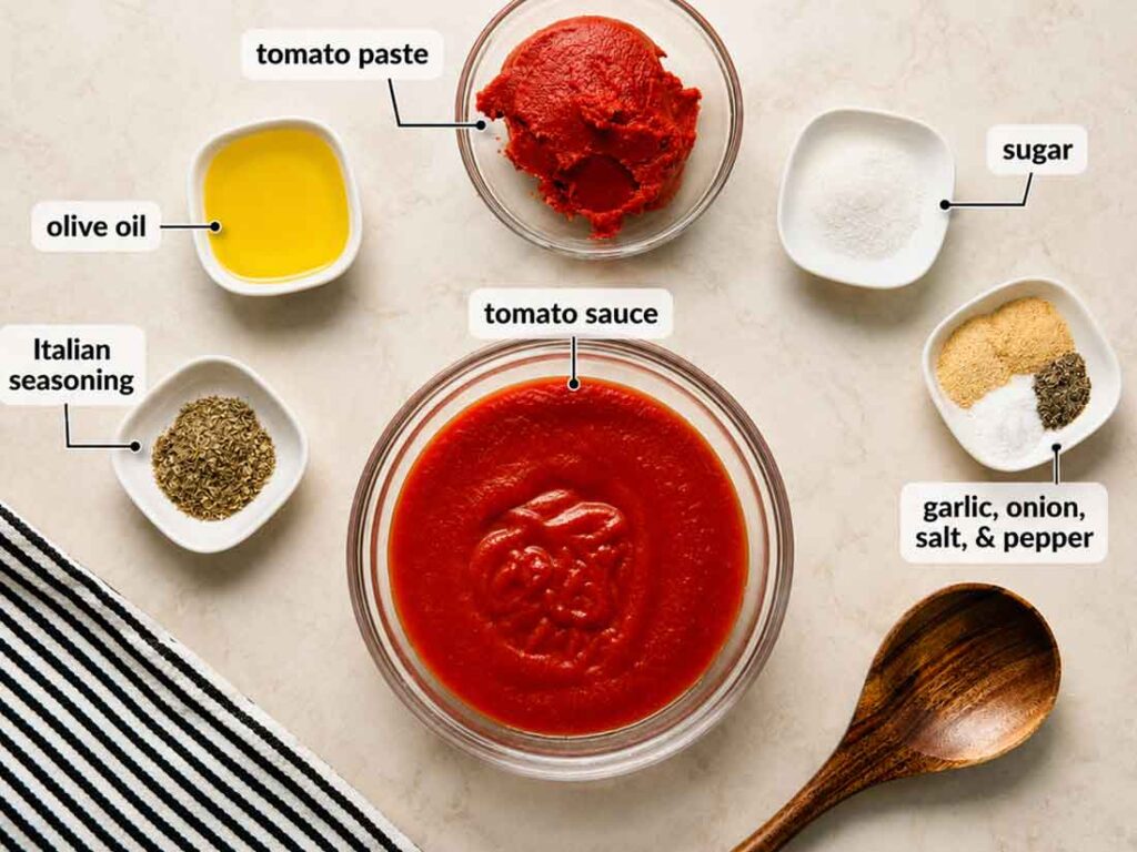 Labeled ingredients for homemade pizza sauce measured into bowls: tomato sauce, tomato paste, olive oil, sugar, Italian seasoning, and a dish of garlic powder, onion powder, salt, and pepper