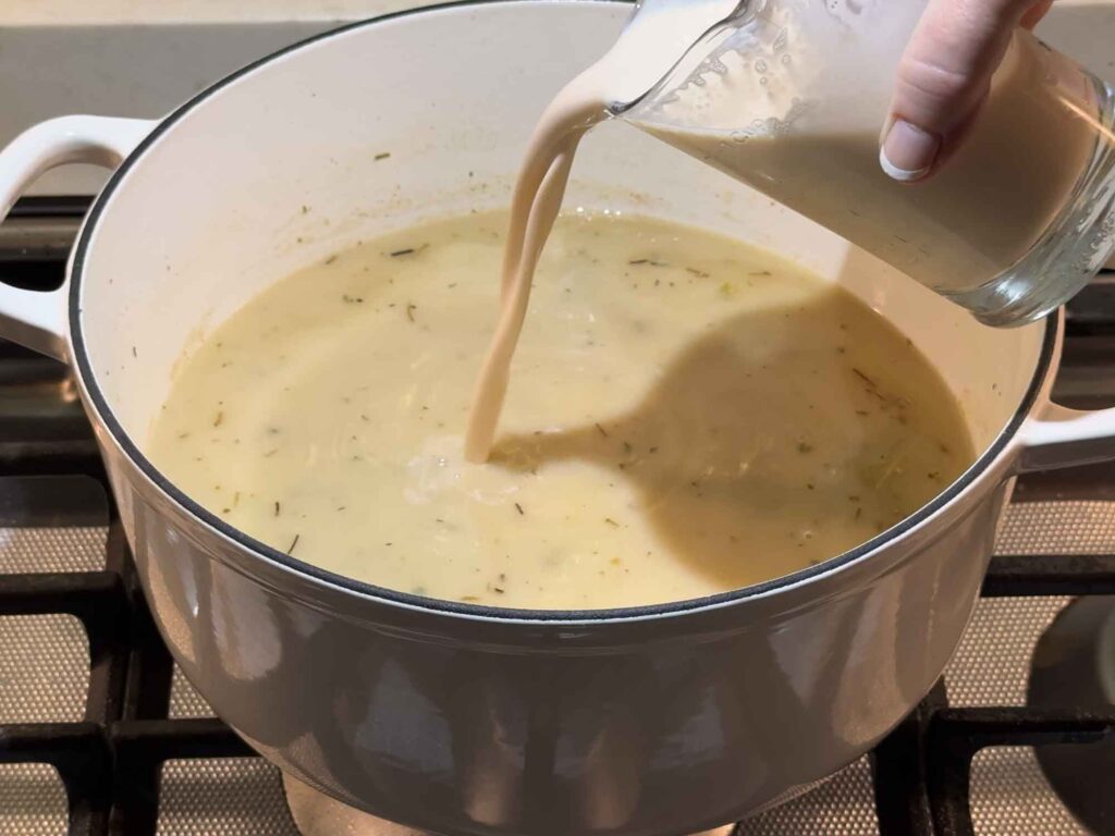 Pouring evaporated milk into the chicken stew