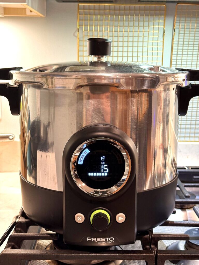 A pressure canner heating on the stovetop, ready to process jars of tomato sauce