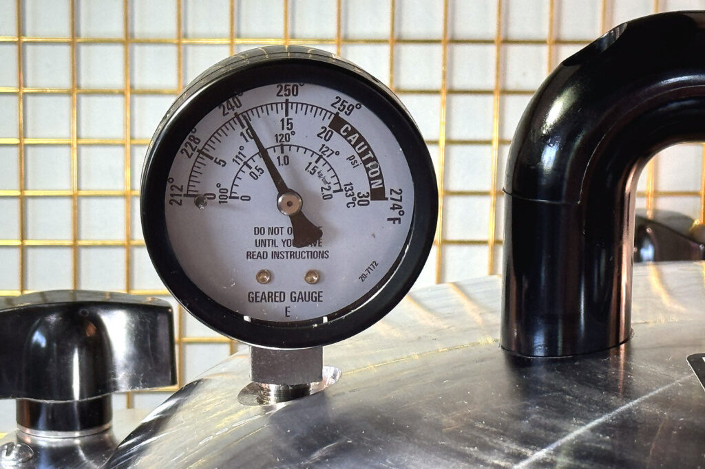 Close-up of the pressure canner dial gauge showing the pressure reading