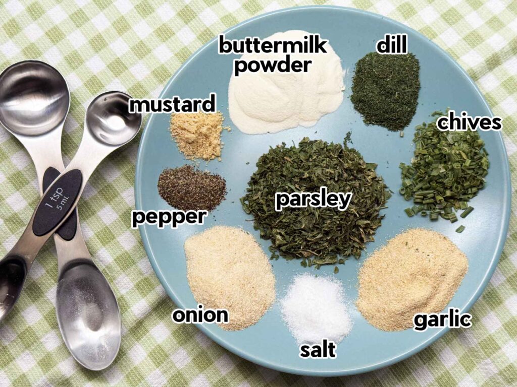 Ingredients to make ranch seasoning on a plate: buttermilk powder, dill, chives, parsley, garlic, onion, salt, pepper, and mustard