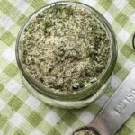 Ranch seasoning in a jar with a measuring spoon and a kitchen towel