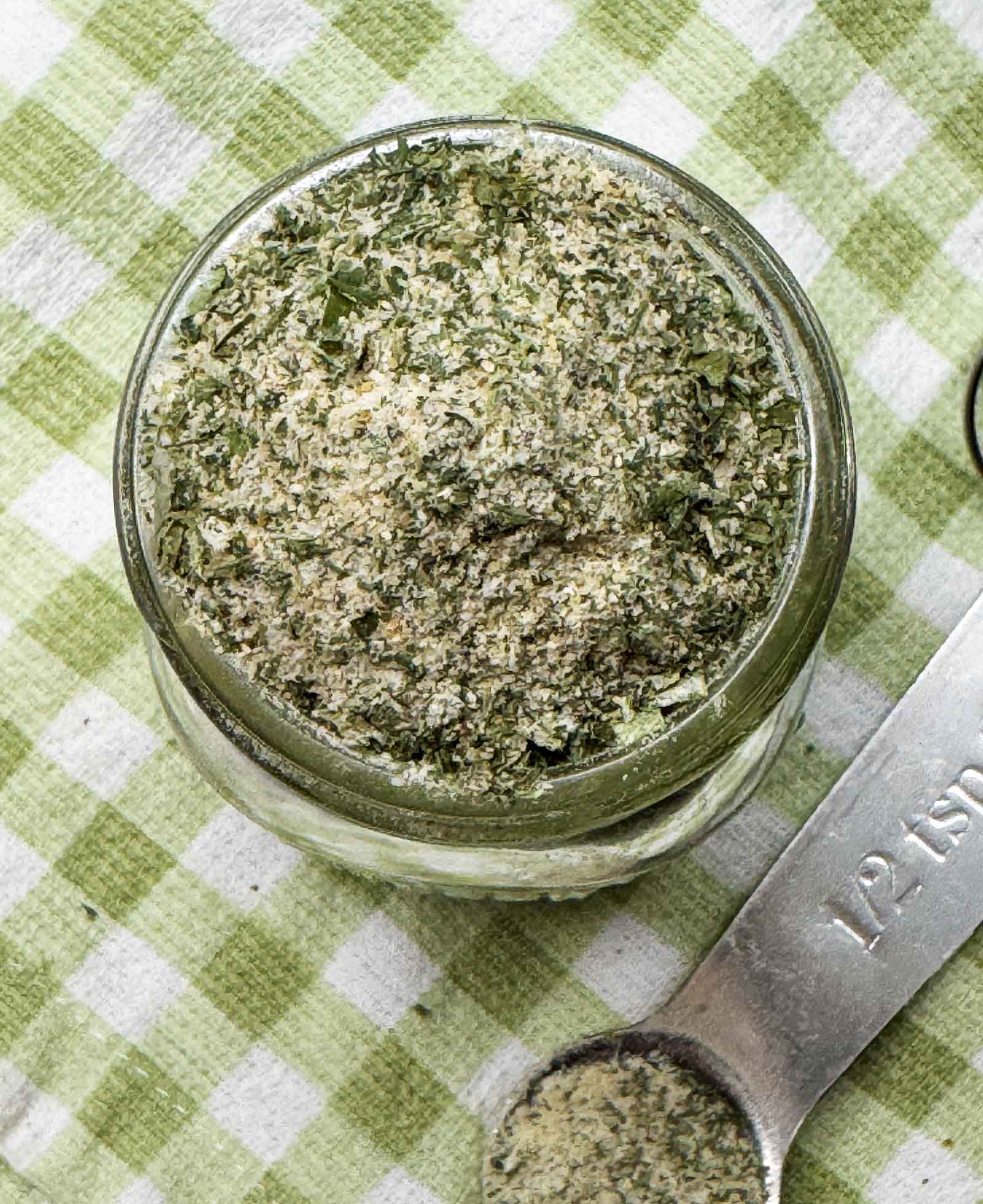 Ranch seasoning in a jar with a measuring spoon and a kitchen towel