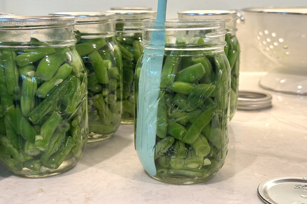 A silicone bubble tool sliding down the inside of a packed jar to release trapped air