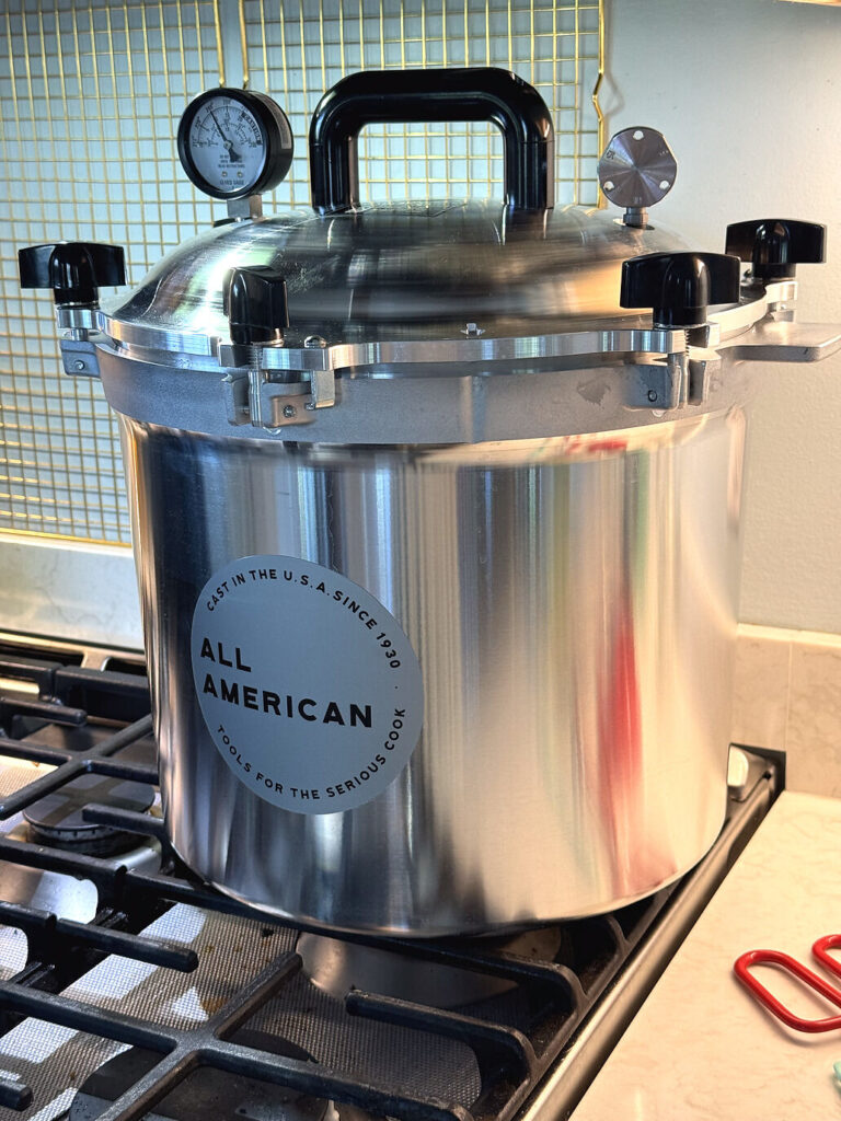 The All American pressure canner closed on the stovetop with its dial gauge on top
