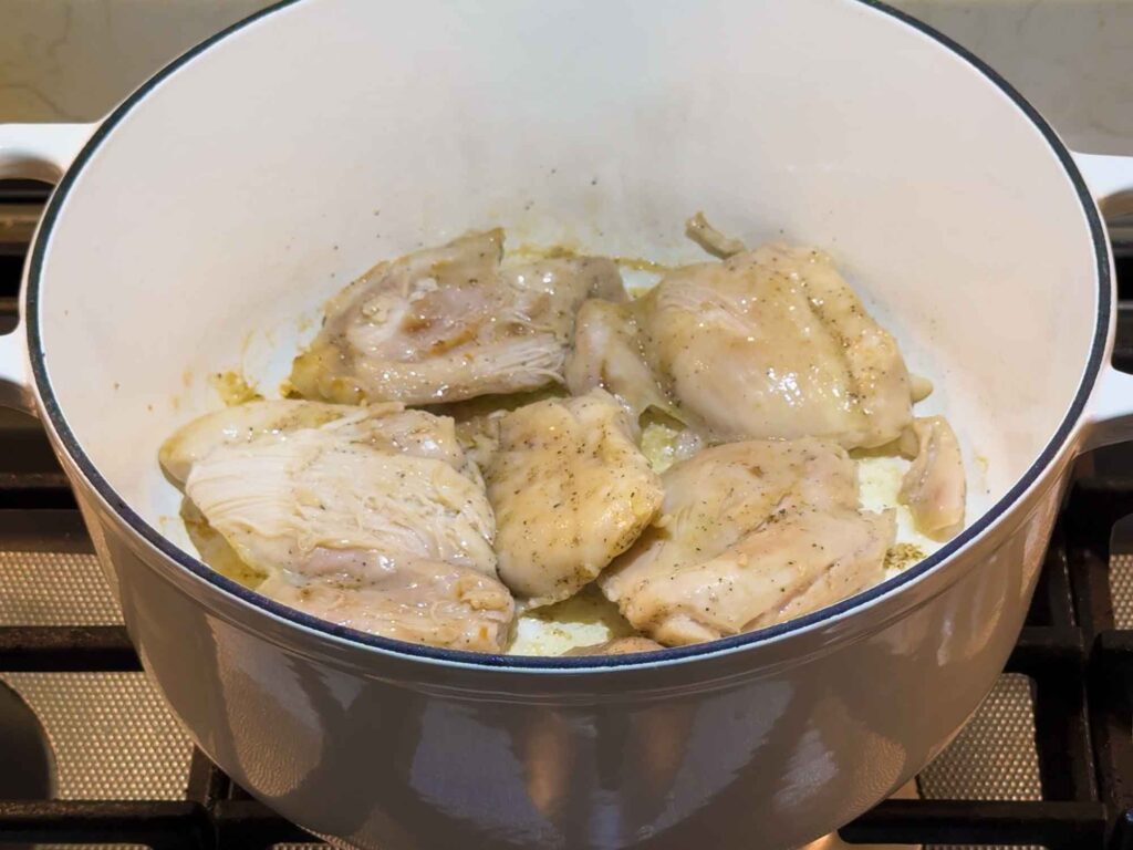 Searing chicken thighs in a large pot to get them browned a bit