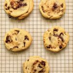Soft, thick sourdough chocolate chip cookies cooling on a wire rack.