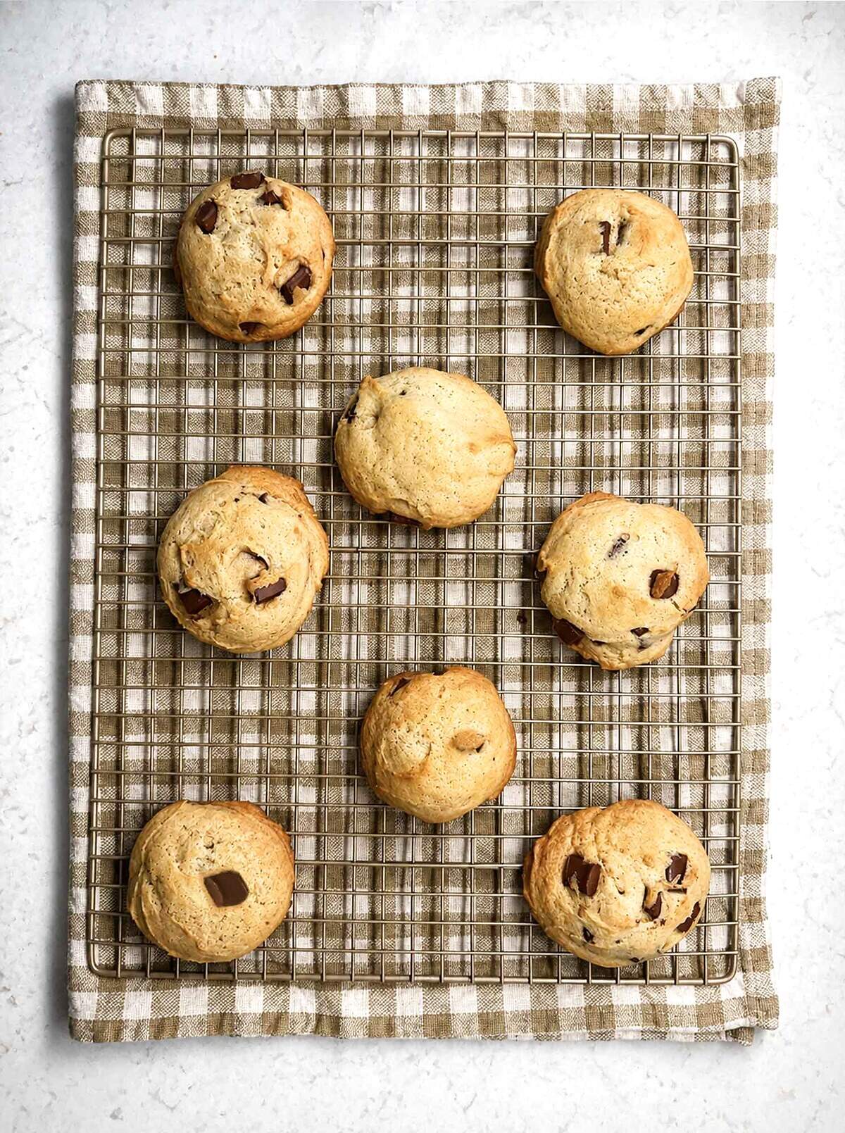 Soft, thick, domed sourdough chocolate chip cookies cooling on a wire rack.