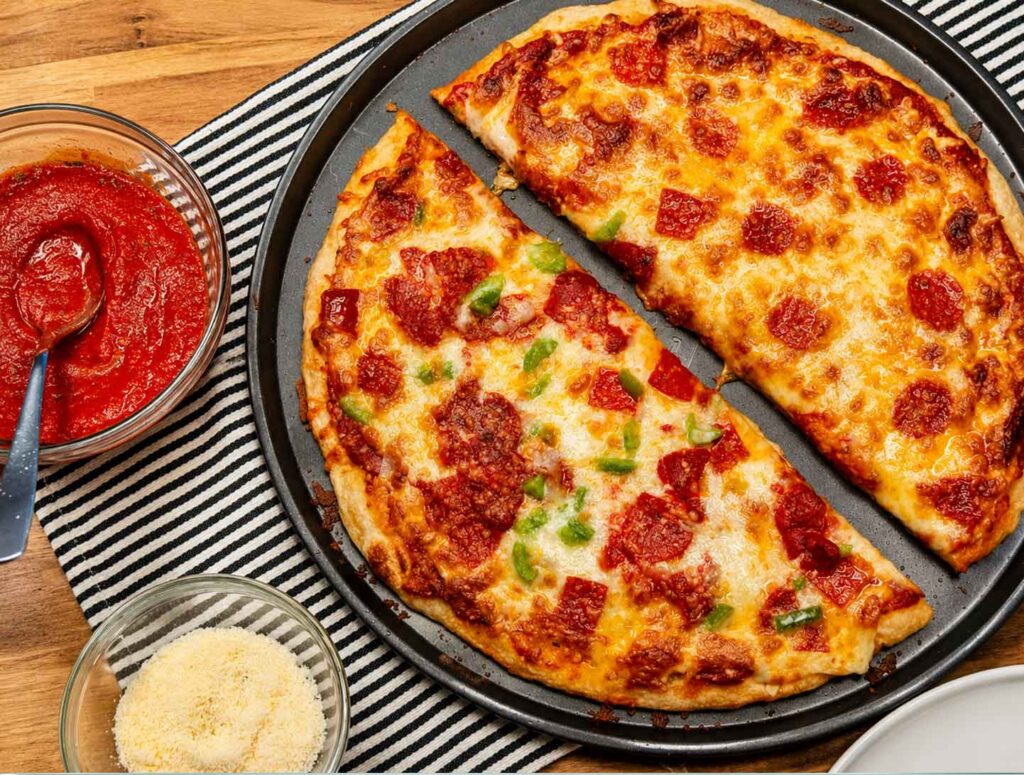 Sourdough pizza dough crust stretched into a 16-inch round pizza pan