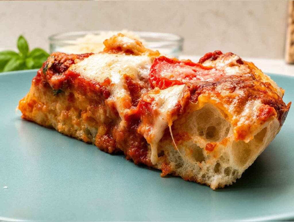 Slice of sourdough pizza on a blue plate topped with mozzarella cheese.