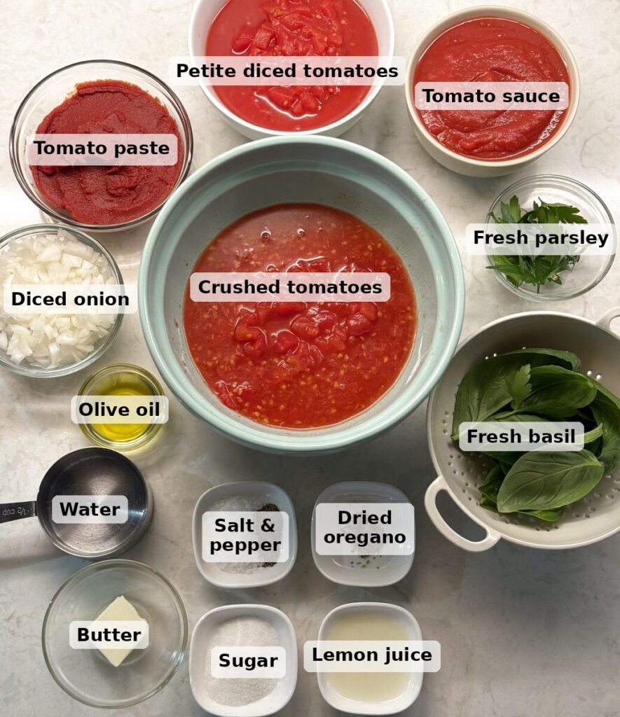 Labeled spaghetti sauce ingredients measured into bowls: tomato paste, petite diced tomatoes, tomato sauce, crushed tomatoes, diced onion, olive oil, water, butter, salt and pepper, dried oregano, sugar, lemon juice, fresh parsley, and fresh basil