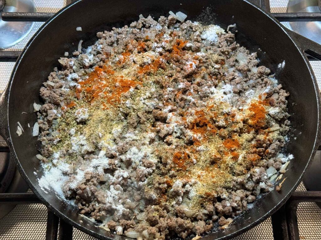 Sprinkling flour and spices over hamburger in skillet