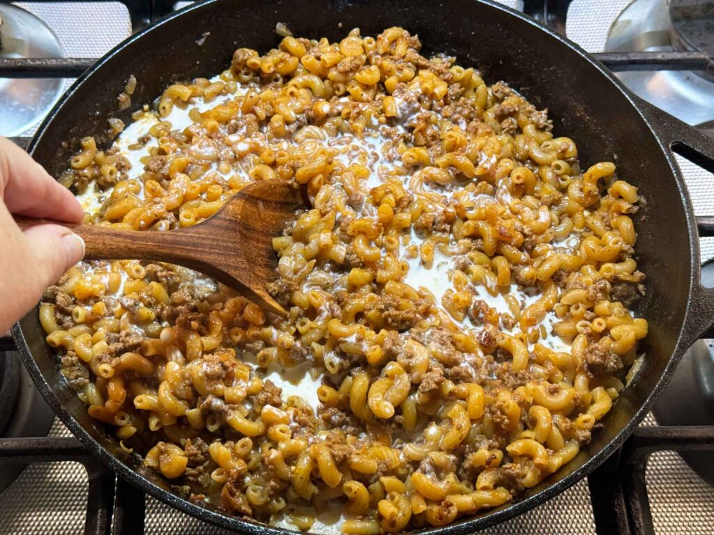 Stirring cream into hamburger helper in skillet