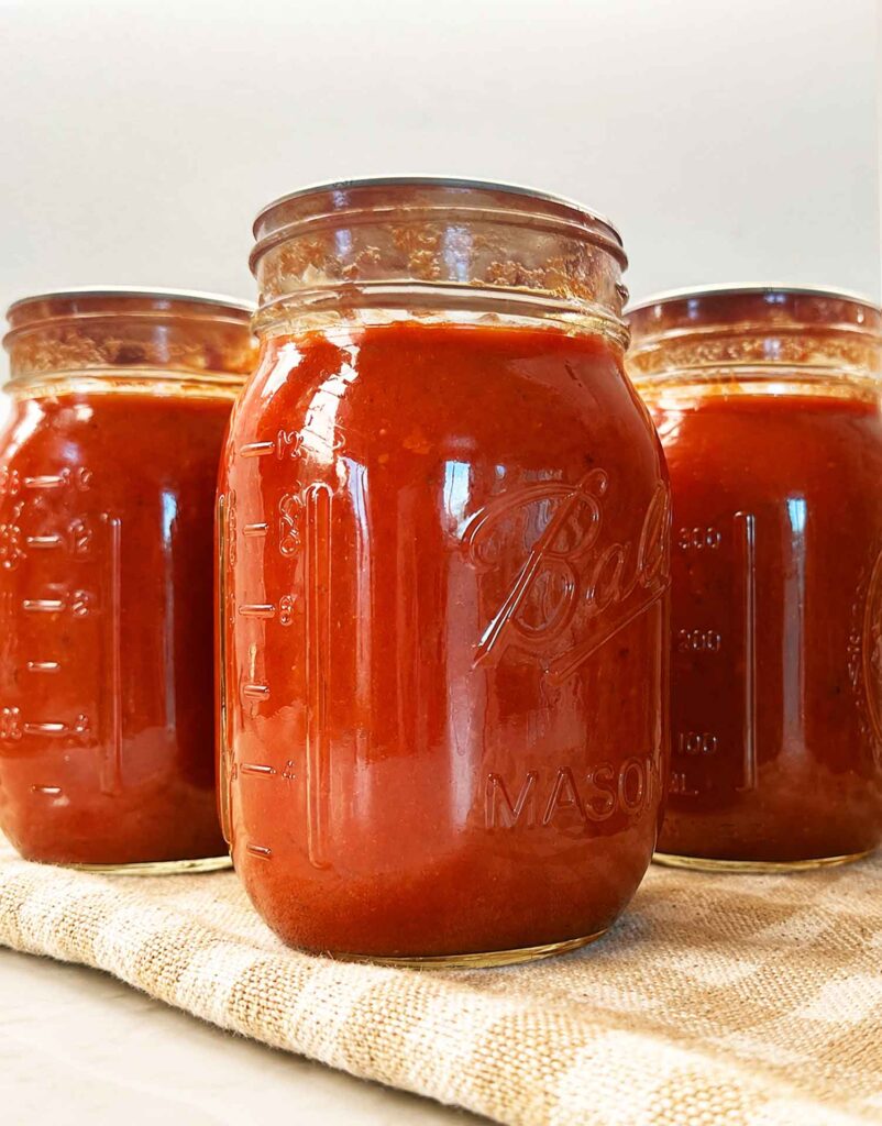 Jars of finished homemade tomato sauce on a napkin