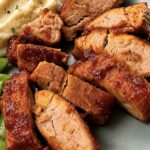 Brown sugar BBQ pork tenderloin sliced into glazed medallions on a plate with mashed potatoes