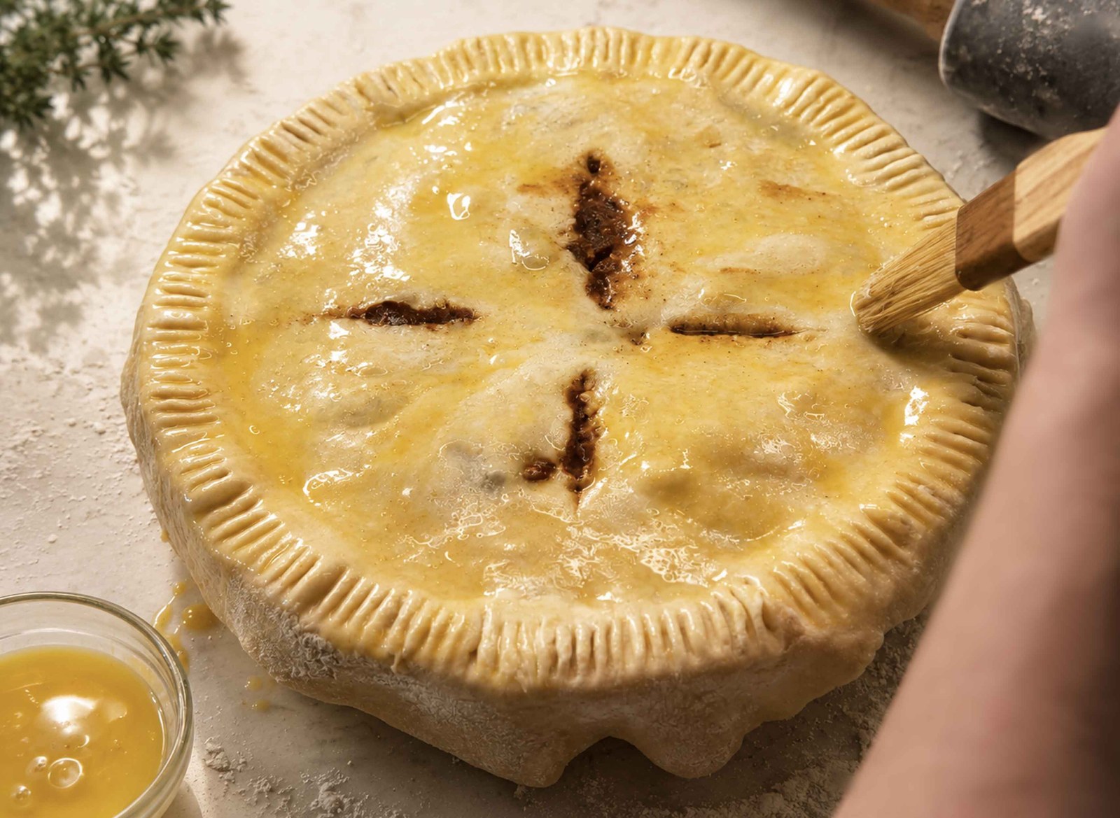 Unbaked beef pot pie brushed with egg wash, with steam slits cut in the top crust