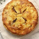 Whole homemade beef pot pie fresh from the oven with a deep golden, flaky top crust